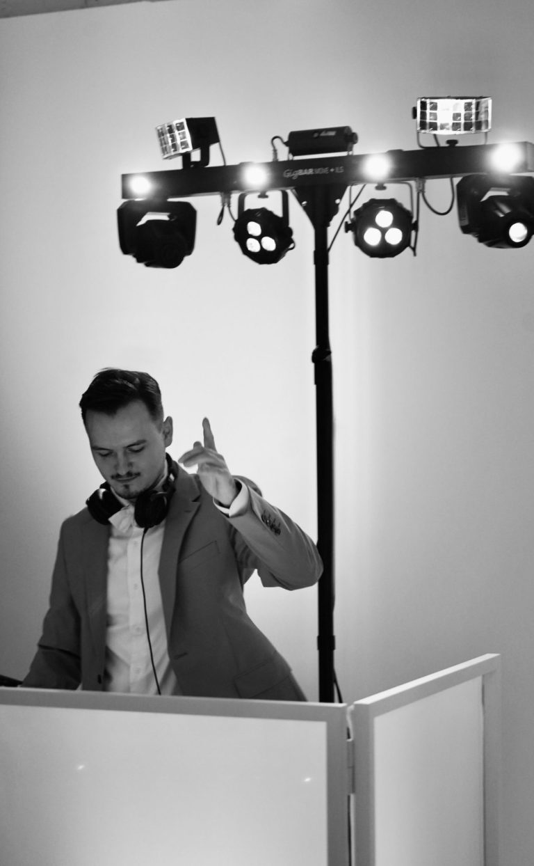 DJ steht an einem Mischpult und bedient Plattenspieler in einem Club. DJ NIIMU im Borussia Park