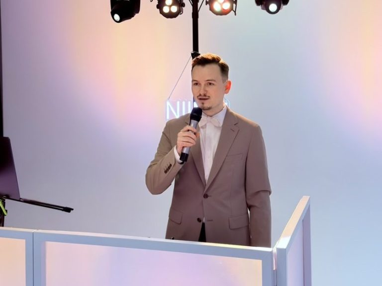 Lächelnder Mann mit kurzem, gestutztem Haar in einem hellgrauen Anzug. NIIMU MUSIC